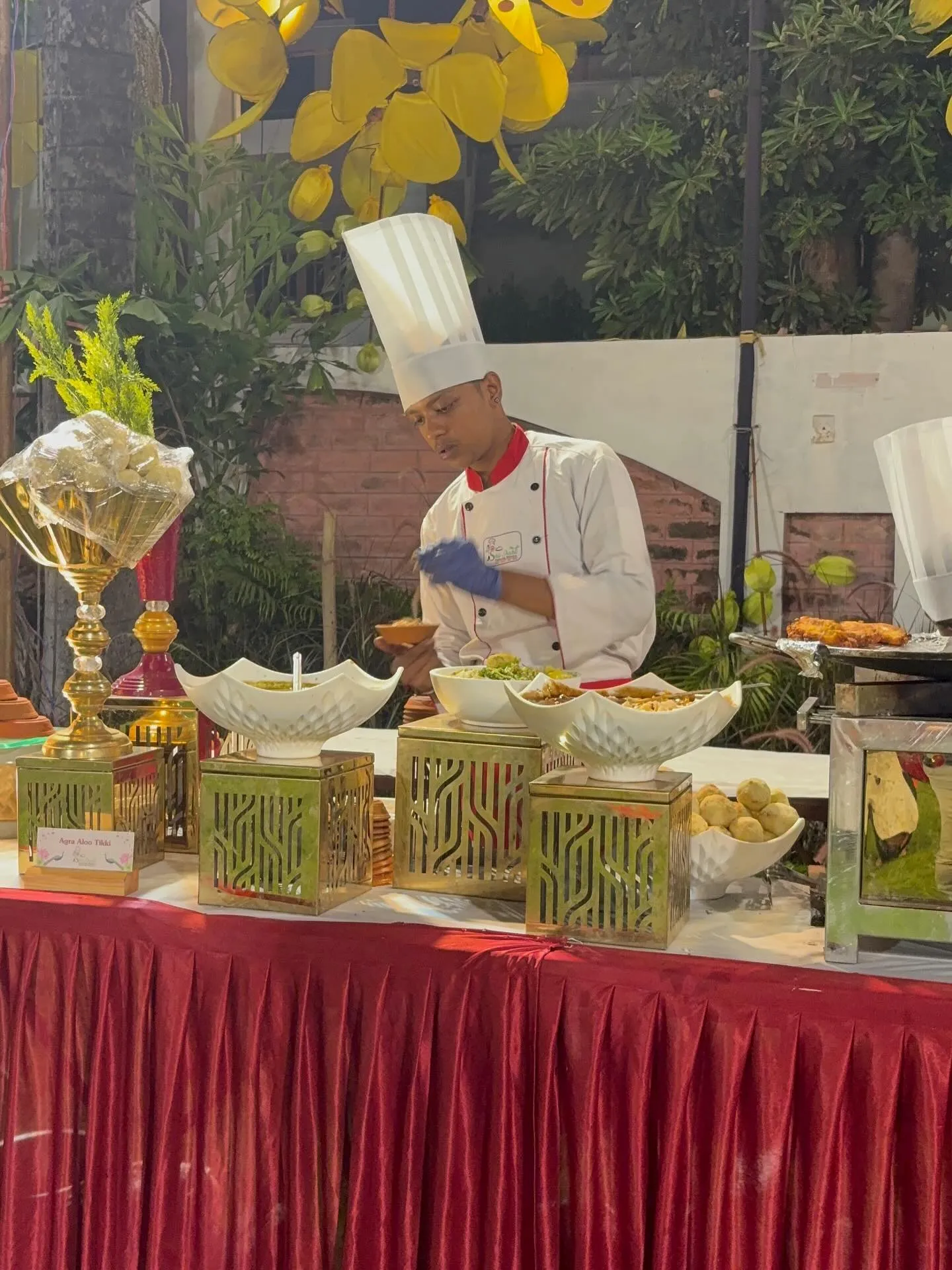 Chef plating chaat at an outdoor evening live counter