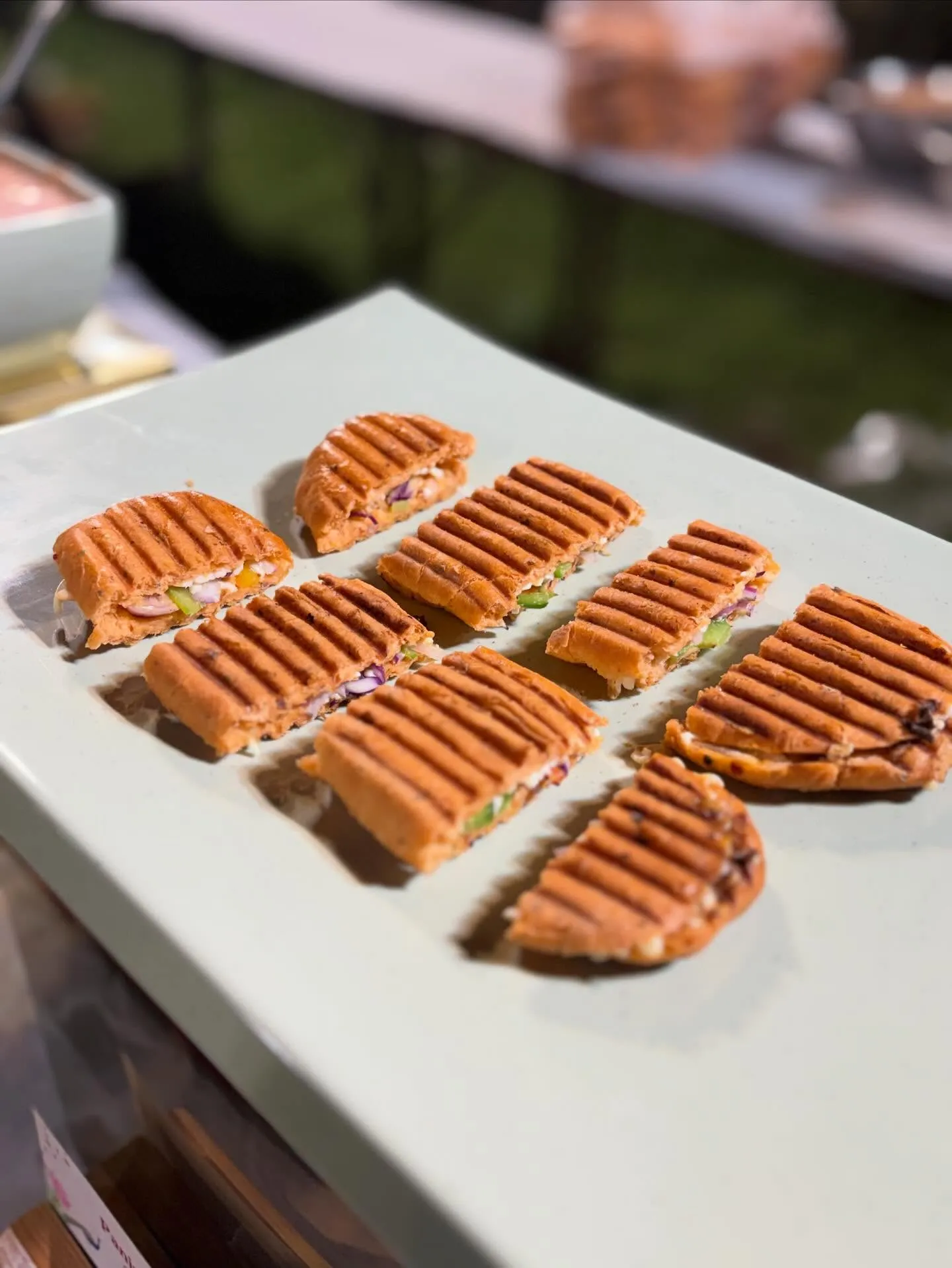 Grilled panini canapés sliced and plated for a live grill counter