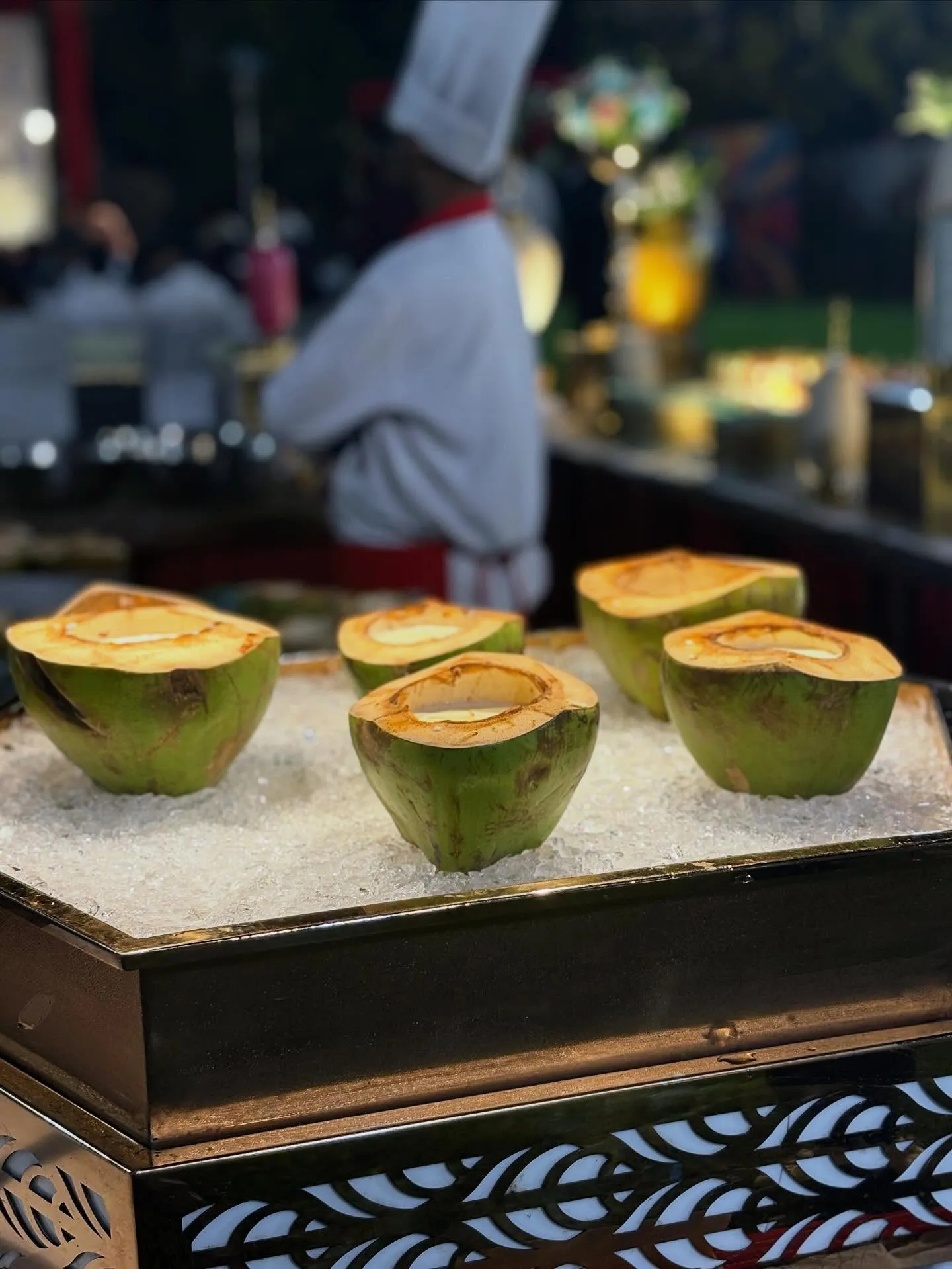 Chilled tender coconut halves on ice at a live beverage counter